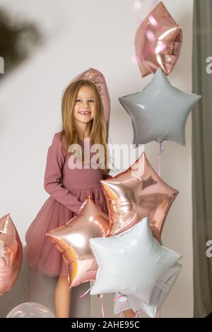 Happy beautiful little girl holding a silver gel balloon in the form of stars. Birthday celebration Stock Photo