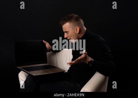 Furious man angry about bad news online or pc software failure, mad helpless office worker having problem with broken laptop, stressed student hates c Stock Photo