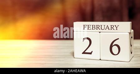 Calendar reminder event concept. Wooden cubes with numbers and month on February 26 with sunlight. Stock Photo
