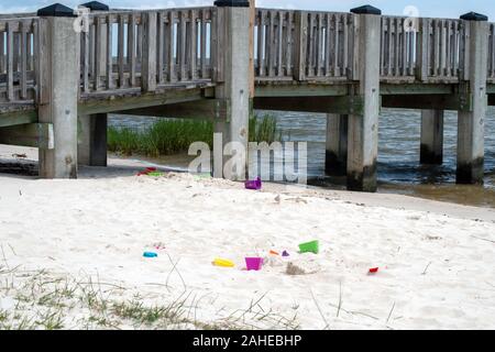 Plastic sand toys abandoned near the pier at a Mississippi ocean on a sunny summer day. Bokeh. Stock Photo