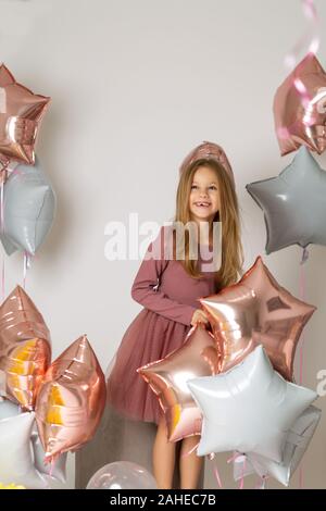 Happy beautiful little girl holding a silver gel balloon in the form of stars. Birthday celebration Stock Photo