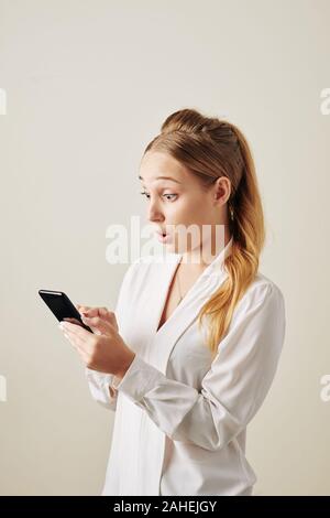 Shocked young woman reading text message with exciting news on smartphone Stock Photo