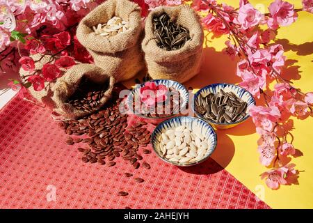 Branches with peach flowers and bowls with watermelon, sunflower and pumpkin seeds on holiday table Stock Photo