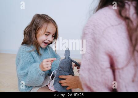 Little girl in a blue sweater playing with doll with her grandma. Stock Photo
