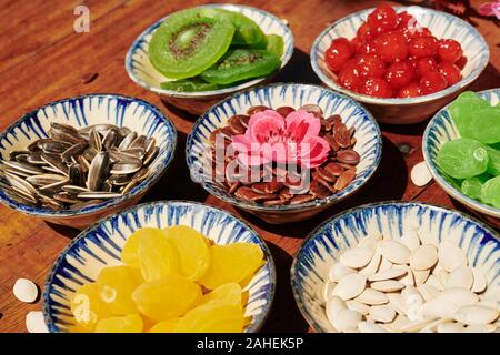 Small ceramic plates with sweet dried fruits and seeds on wooden table Stock Photo