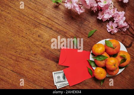 Peach branches, tangerines and lucky money envelopes on table for Chinese New Year celebration Stock Photo