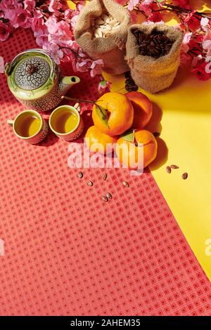 Table with herbal tea, tangerines and sacks with various seeds prepared for Chinese New Year celebration Stock Photo