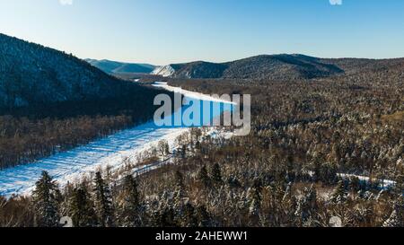 Aerial image from the top of snowy mountain pines in the middle of the winter. Stock Photo