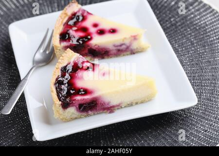 Two slices of black currant cheesecake on a white rectangular plate Stock Photo