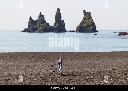 Woman Walking Along the Beach Looking at the Prominent Sea Stacks in Vik, Iceland Stock Photo