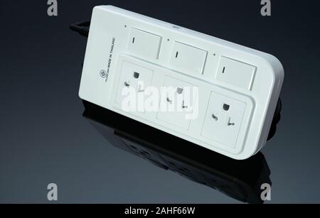 Power strip with three electrical standard socket on black background. White universal plug with overload protection. Fire resistant material for cove Stock Photo