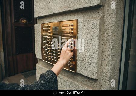 Female hand presses the intercom button to access inside. Stock Photo