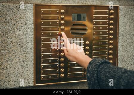 Female hand presses the intercom button to access inside. Stock Photo