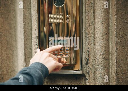 A male hand presses a doorphone button for access inside. Stock Photo