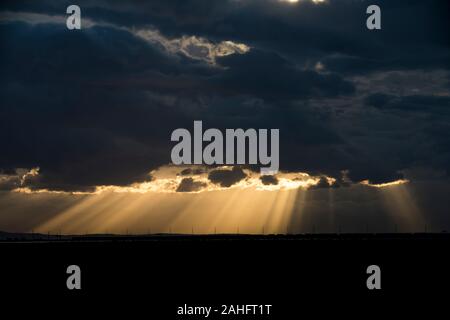 Rays of sunlight penetrating dark storm clouds Stock Photo