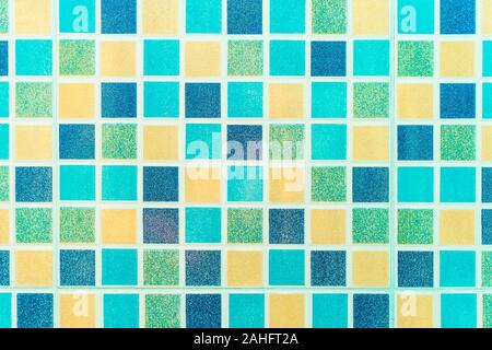 Multiple colored square mosaic tiles texture with white filling decorate the wall in the bathroom. Stock Photo