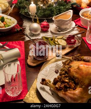 A close up of a dining table dressed with a complete Christmas turkey dinner including cranberry sauce and gravy ready for eating. Stock Photo