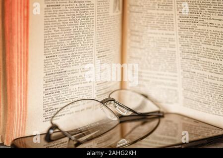 12 January 2019, Saint Petersburg, Russia. Composition with old dictionary (Larousse illustre, Paris, 1928), glasses and smartphone Stock Photo