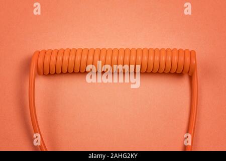 Orange spiral cable on orange background. Abstract communication and connection theme still life Stock Photo