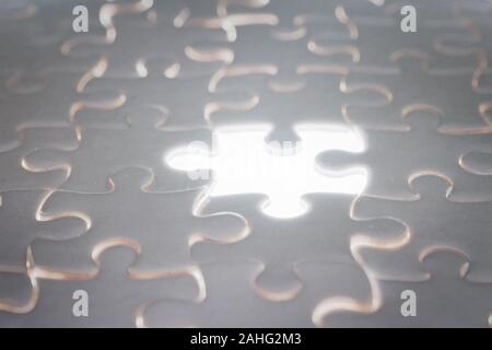White blank jigsaw puzzle with blank illuminated piece. Selective focus Stock Photo