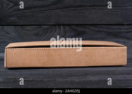 Small cardboard box on the black wooden table. Selective focus Stock Photo