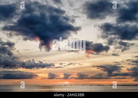 Sunset over sea. Dark dramatic clouds and distant yachts at sunset Stock Photo