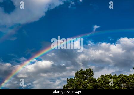 Rainbow against a blue sky with clouds Stock Photo
