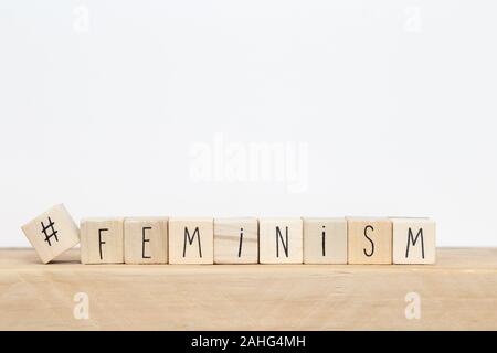 Wooden cubes with a hashtag and the word Feminism near white background, social media concept Stock Photo