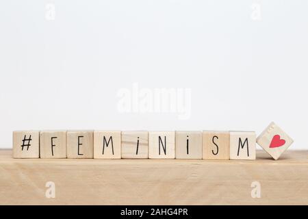 Wooden cubes with a hashtag and the word Feminism near white background, social media concept Stock Photo