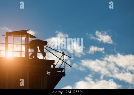 Construction Workers Silhouette on Roof of Building. Stock Photo