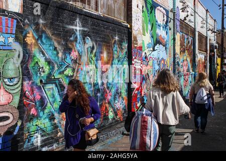 People strolling through Clarion Alley with famous Mission murals on the walls in San Francisco, United States of America Stock Photo