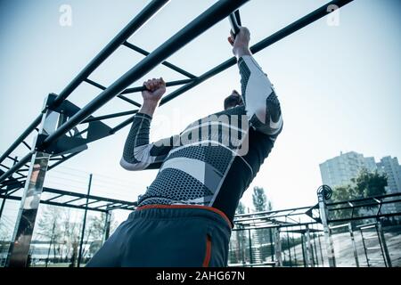 Strong sportsman training his muscles and doing chin ups Stock Photo