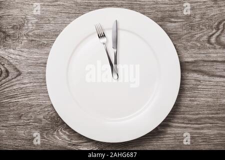 Empty ceramic plate and cutlery on a wooden table, top view. Concept on the topic: time to eat Stock Photo