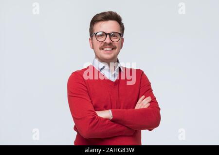 man in red sweater and glasses standing in front of camera, feeling positive, confident Stock Photo
