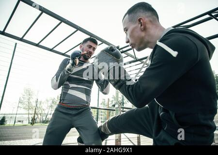 Two boxers looking serious while fighting outdoors at the training Stock Photo