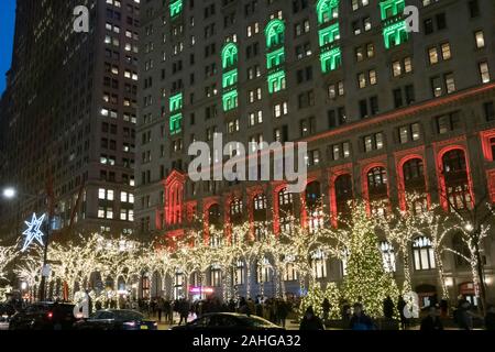 Zuccotti Park with the Trinity and United States Realty Buildings in the background is brightly lit at Christmas Season, NYC, USA Stock Photo