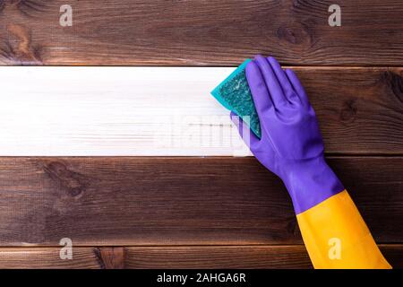 A hand in a rubber glove washes a wooden surface. Cleaning, room cleaning. Stock Photo
