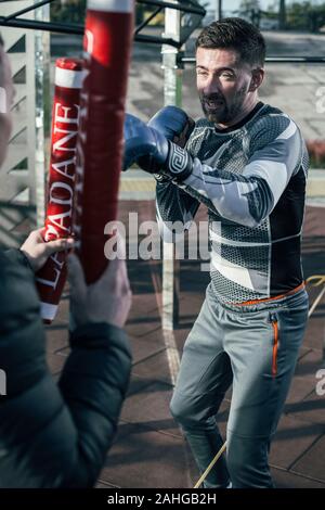Skilled sportsman making the punch during boxing training outdoors Stock Photo