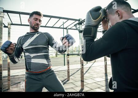 Serious boxer looking tired while training with partner Stock Photo