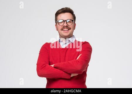 man in red sweater and glasses standing in front of camera, feeling positive, confident Stock Photo