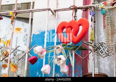 Iron bars of the old house. It has ornaments with red hearts and fake roses. Stock Photo