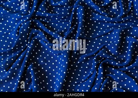 Wrinkled marine blue fabric with white dots. Creased textile, fashion swatch, background texture, seamless concepts Stock Photo