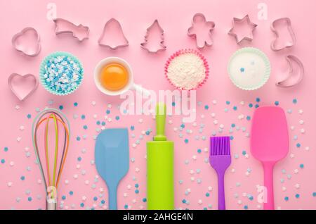 ingredients for baking and kitchen tools with cookie cutter on pink background, flat lay Stock Photo