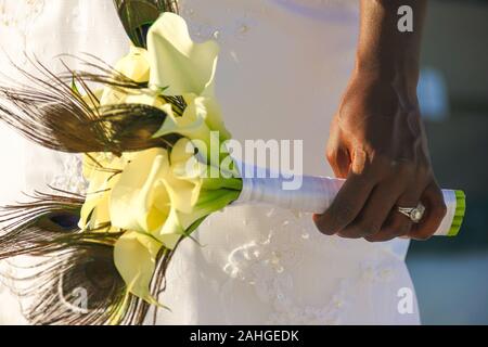 Hand of African American bride with wedding ring holding flower bouquet. Lady on most special day event, ceremony concepts Stock Photo