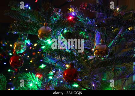 Close-up of part of a Christmas tree with decoration, Christmas baubles, tinsel, stars, and fairy lights, Haslemere, Surrey, UK. Stock Photo