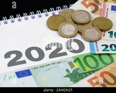 euro banknotes and coins on calendar 2020, concept of expenditure or taxes payment, cost in the new year Stock Photo