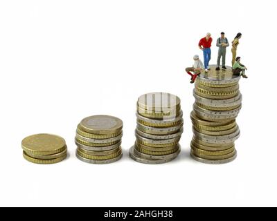 miniature people sitting on biggest stack of coins, concept of financial independence Stock Photo