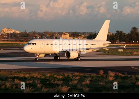 Air travel and civil aviation. Unmarked Airbus A320 passenger jet plane on runway at sunset. No airline title, livery or logo visible. Stock Photo