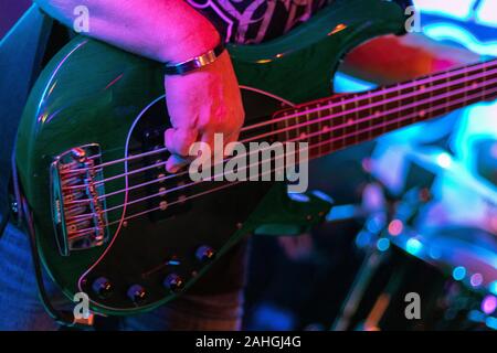 Closeup photo of bass guitar player hands, soft selective focus, live music theme Stock Photo