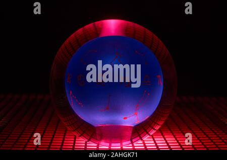 Glass ball photographed on a perforated plate with red light. Stock Photo